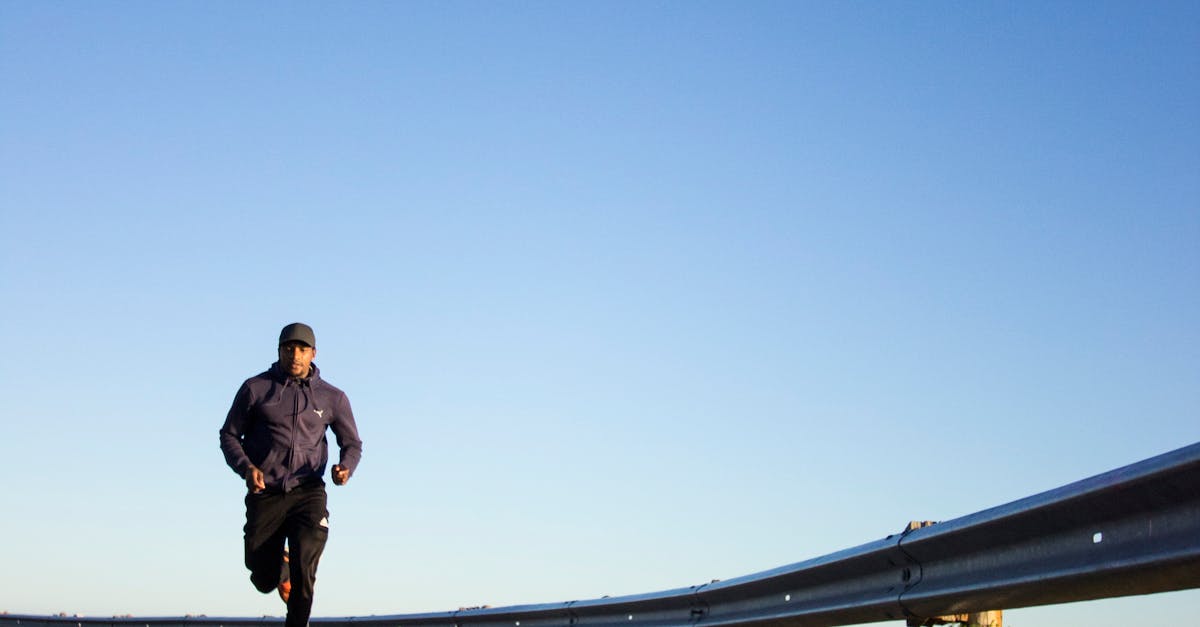 An athletic man jogging on an open road with a clear blue sky in Cape Town, South Africa.